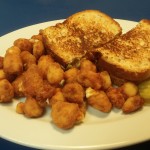 Tuna melt, cheese curds, and 2 pickle chips on a plate.