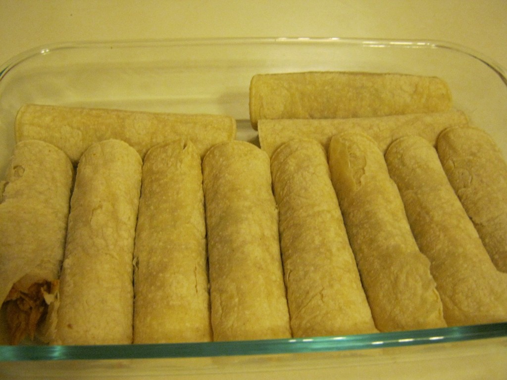 Enchiladas in pan waiting for sauce and cheese